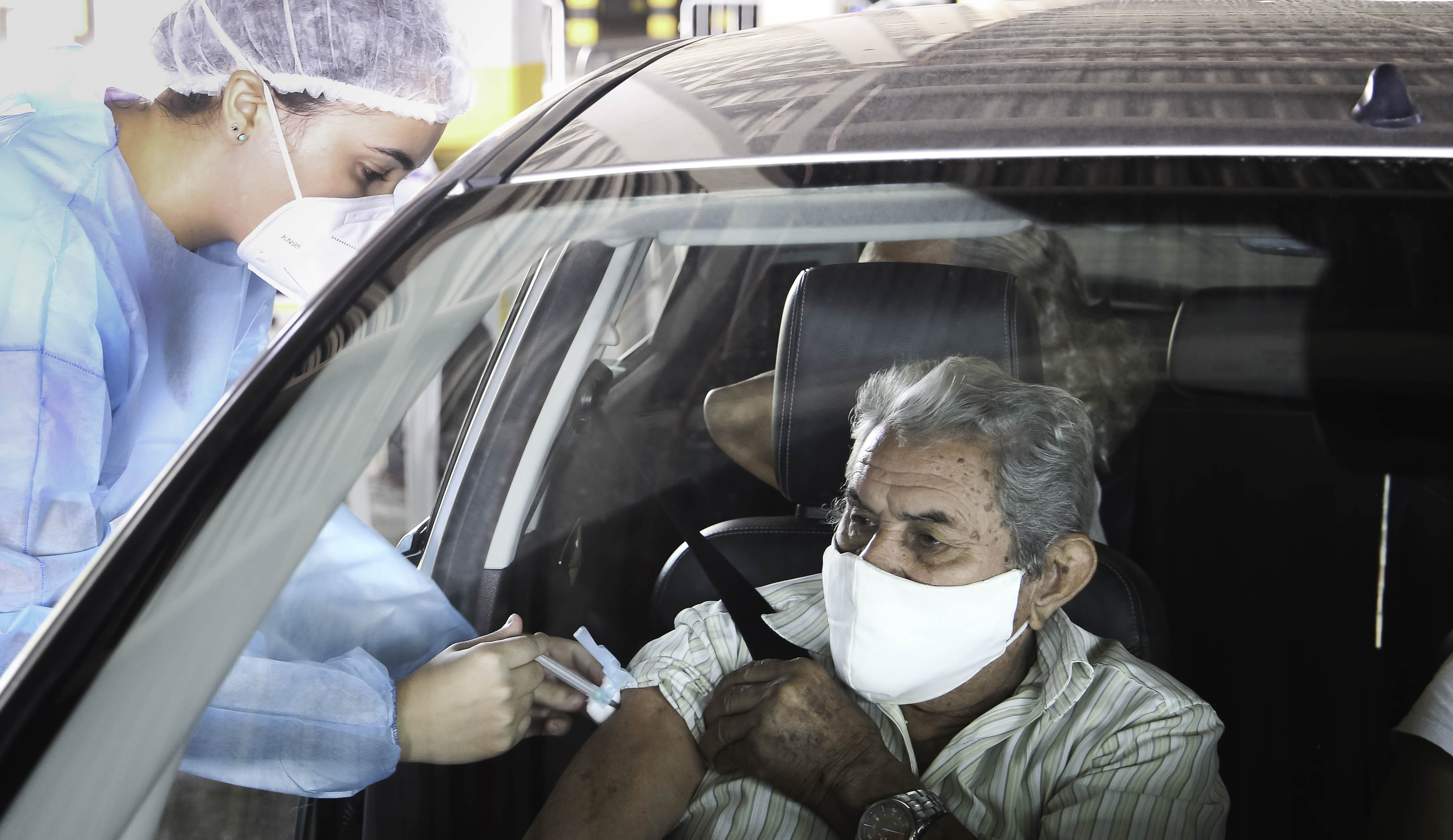 enfermeiro vacina um senhor dentro do carro